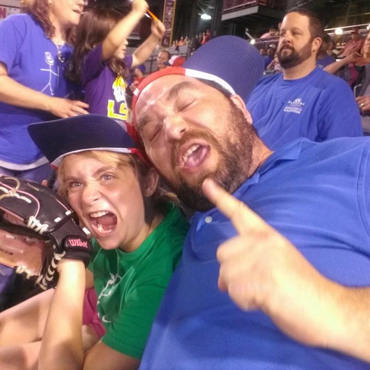 A young blonde girl (the author) and her father at a baseball game.